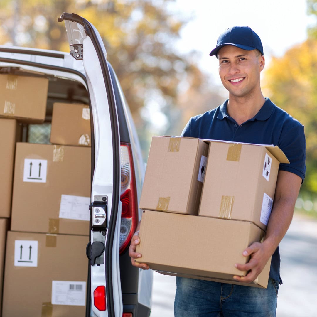 Personalized Delivery Service Delivery person holding boxes with a smile while unloading a van.